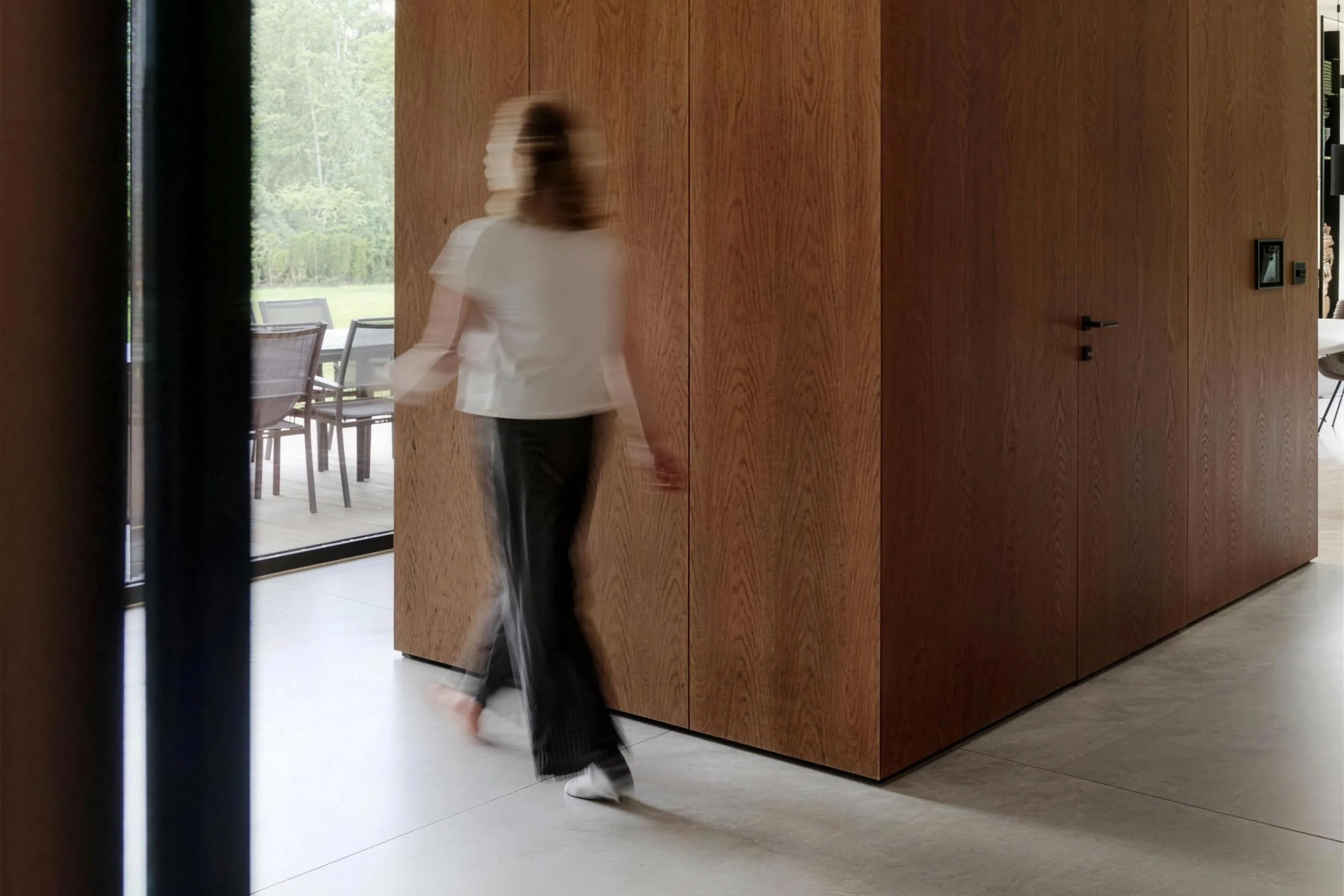 Volume revestido em madeira com porta embutida, e uma pessoa passando em movimento